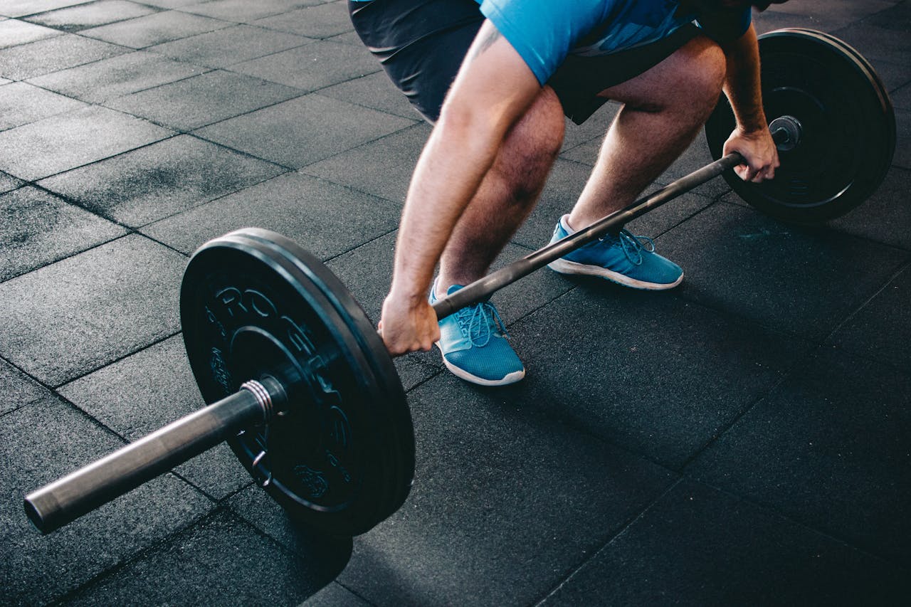 A man deadlifting a barbell indoors showcasing power, fitness, and dedication.